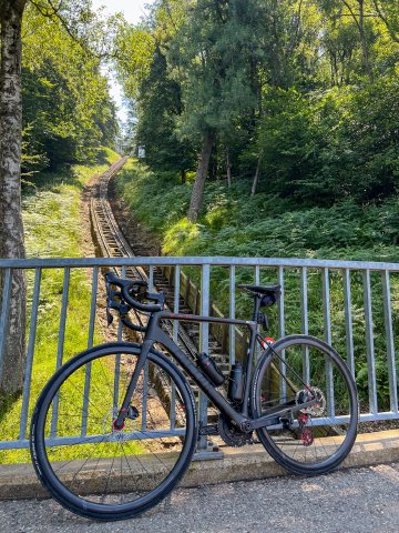 The conductor running one coming down waved to me that day, haha Bicycle leaning against a fence with the Monte Brè funicular track behind along the road to the Punto Panoramico in Lugano, Switzerland