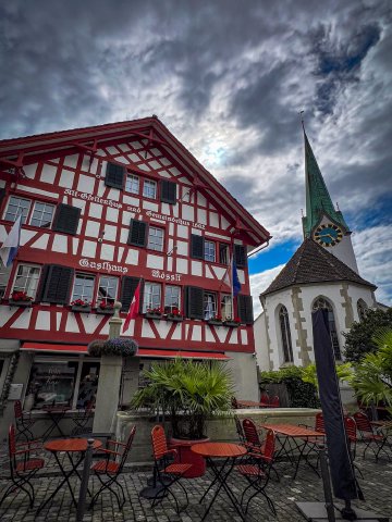 Close up shot of the restaurant Rössli in Zürich, Switzerland with clouds and clock tower in the background