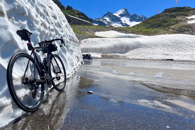 Bicycle leaning against a snowbank at the top of the Sustenpass