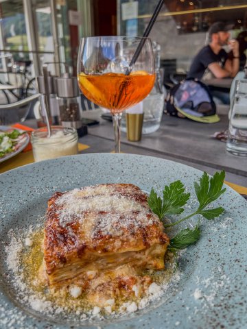 Lasagna and aperol spritz on a table in Airolo, Switzerland