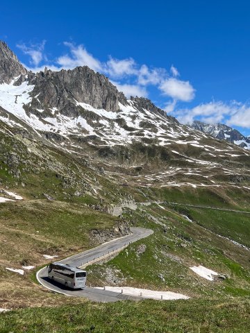 Bus along the Furkapass road with Swiss Alps in the background