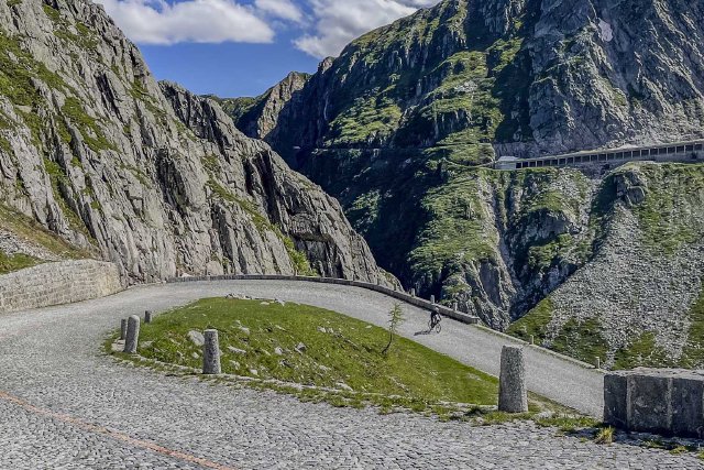 Cyclist descending the cobbled road of the Gotthardpass