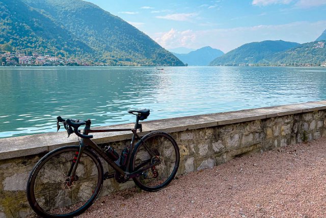 Bicycle leaning against short stone wall next to Lake Lugano