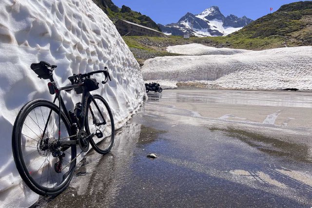 Bicycle leaning against a snow drift at the top of the Sustenpass