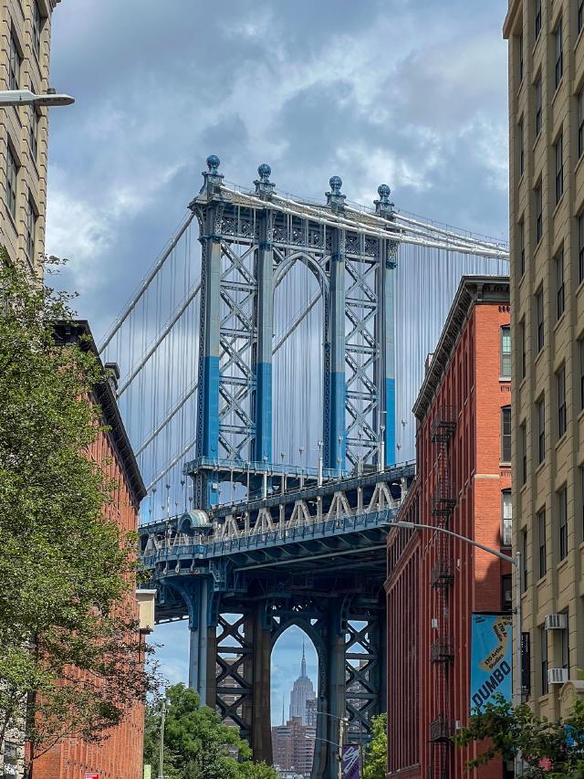 Iconic view of the Manhattan Bridge with the Empire State Building peeking through the bottom.