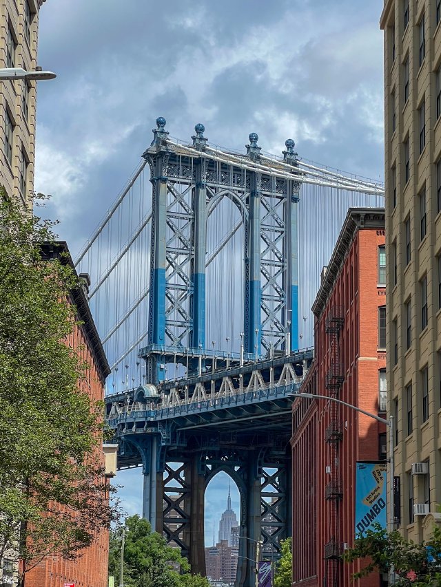 Iconic view of the Manhattan Bridge with the Empire State Building peeking through the bottom.