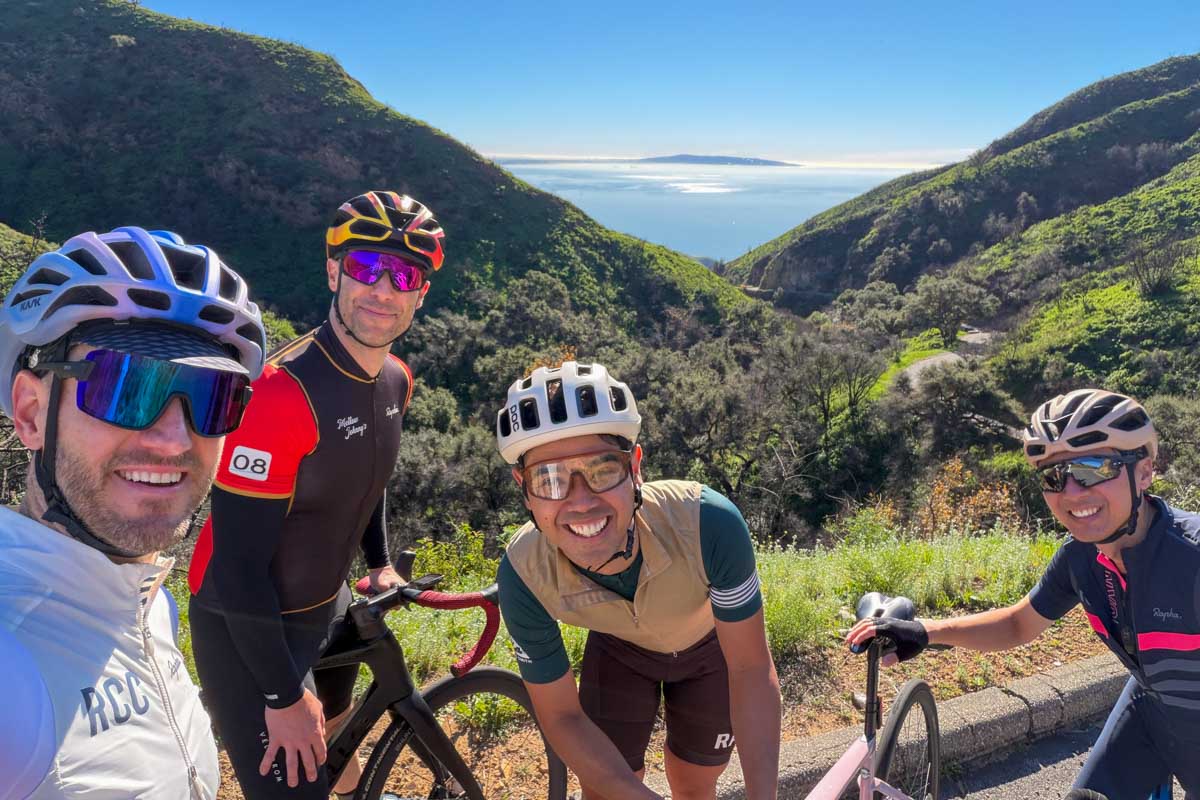 Four cyclists posing for a view over the Pacific Ocean on Tuna Canyon road in the Santa Monica mountains of Los Angeles.
