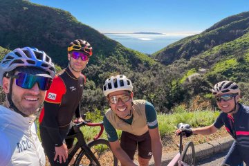 Such a view from Tuna Canyon! Four cyclists posing for a view over the Pacific Ocean on Tuna Canyon road in the Santa Monica mountains of Los Angeles.